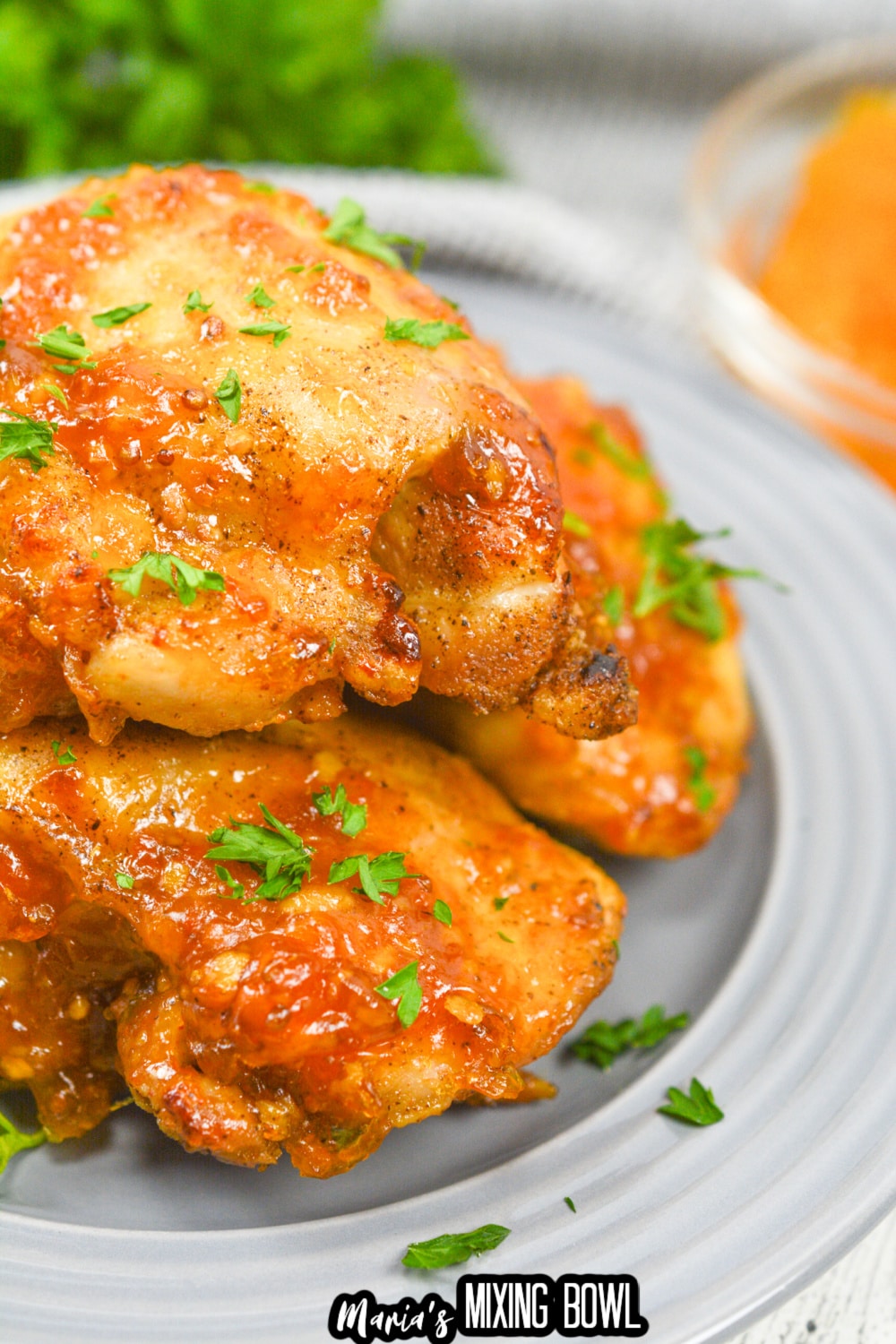 apricot glazed chicken thighs stacked on a gray plate