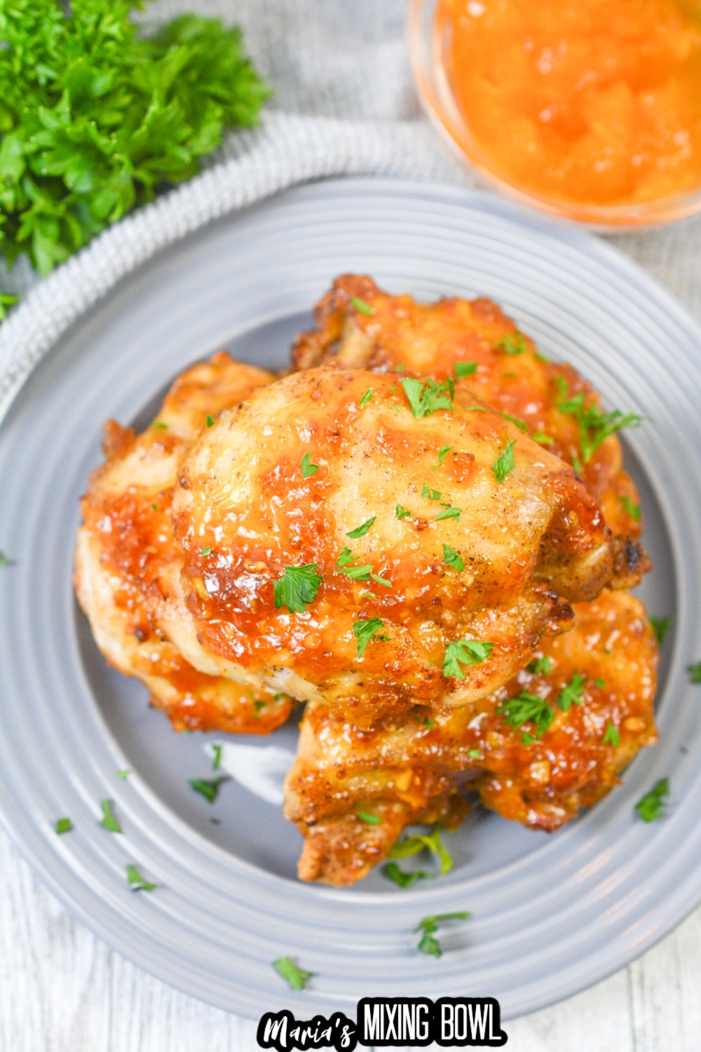 apricot glazed chicken thighs stacked on a gray plate