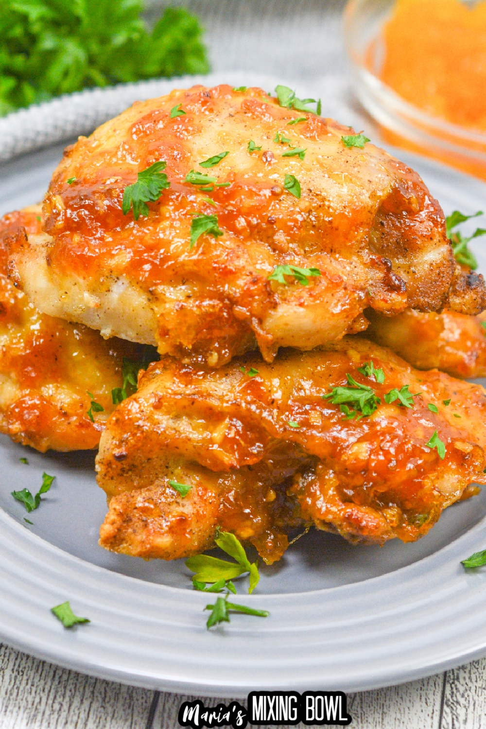 apricot glazed chicken thighs stacked on a gray plate