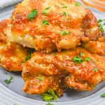 apricot glazed chicken thighs stacked on a gray plate