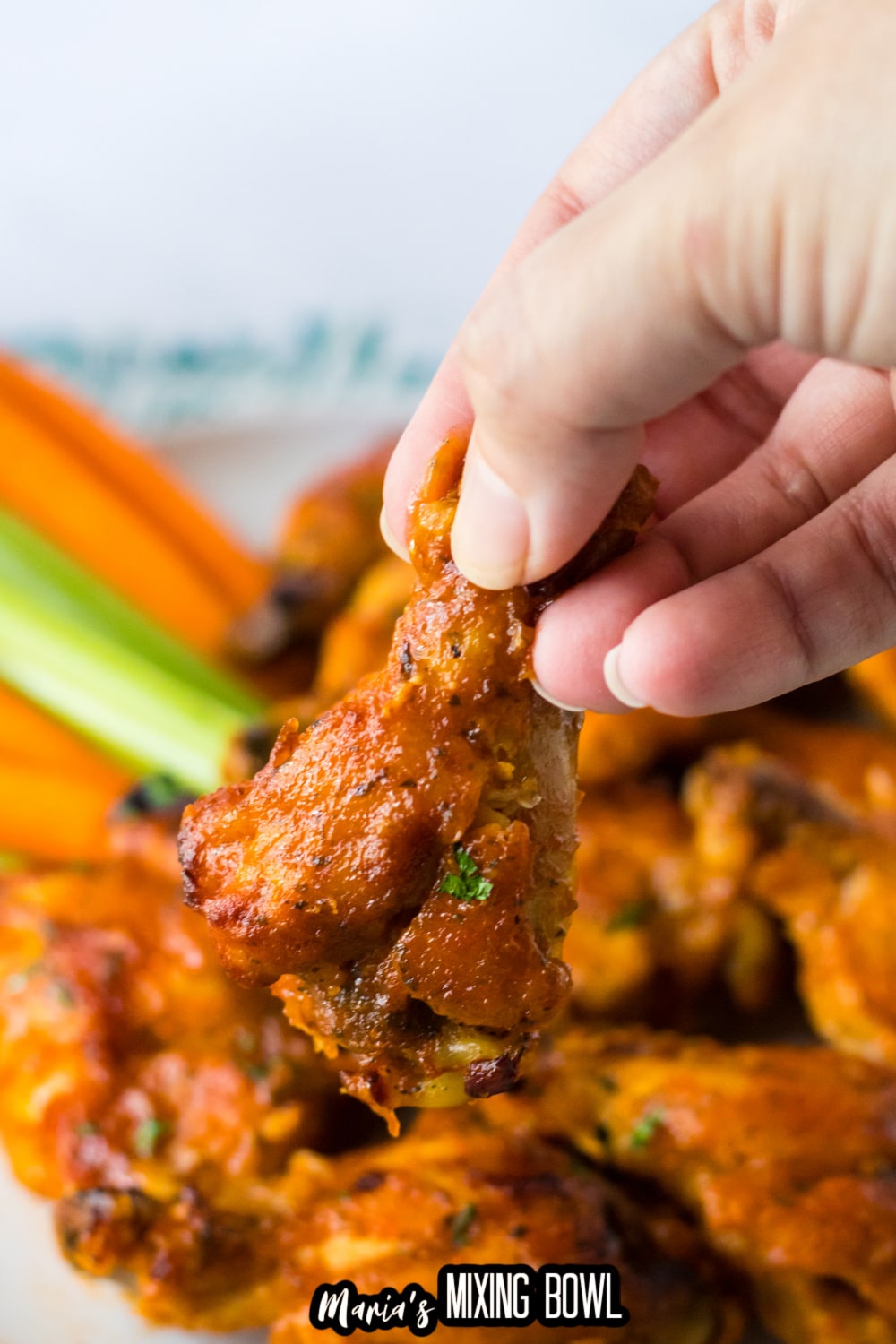 buffalo ranch chicken wing held in the air in a woman's hand