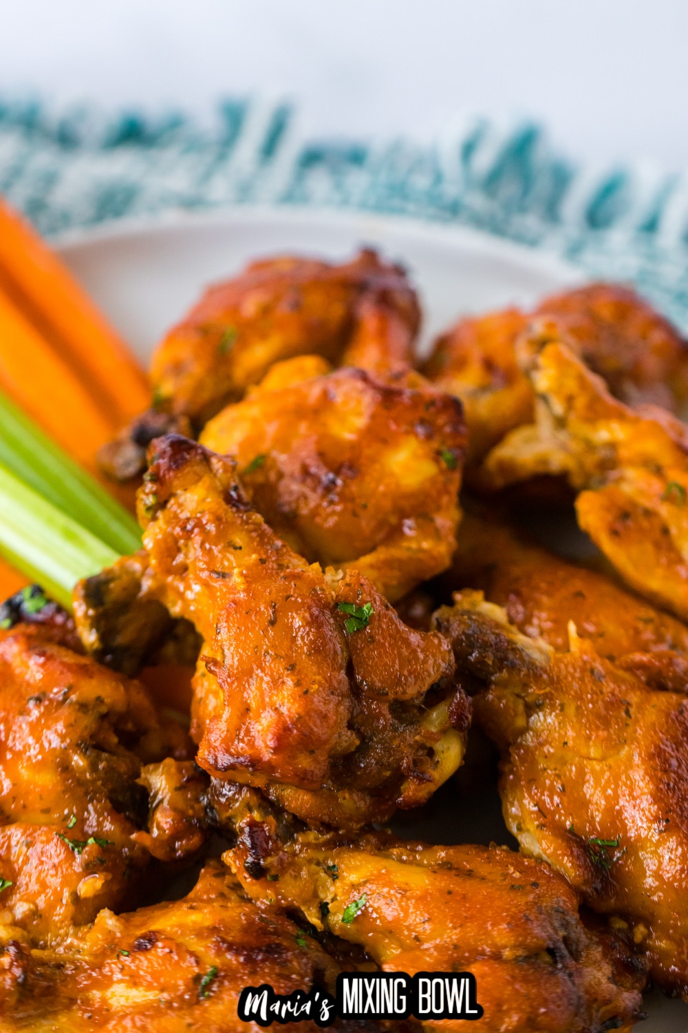 stack of chicken wings on a white plate with celery and carrot sticks