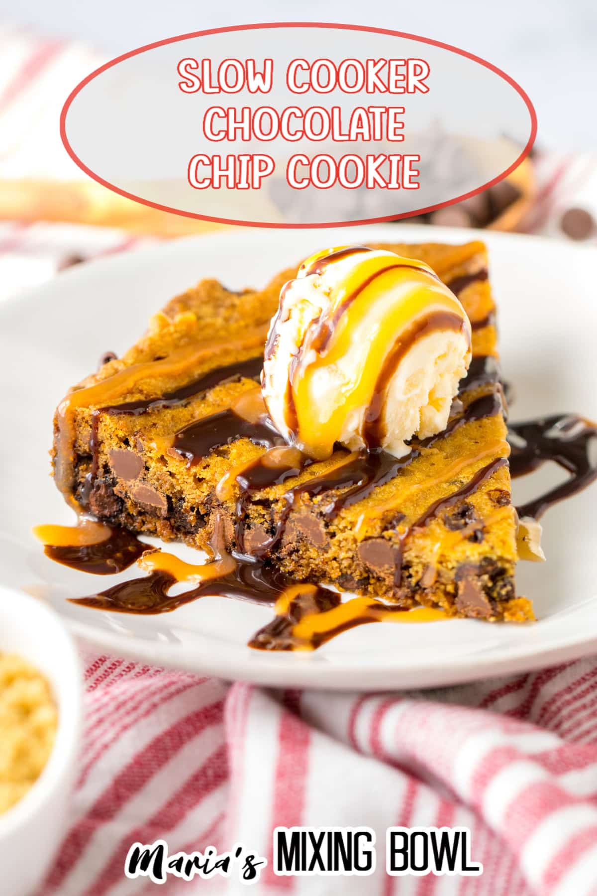 slice of cookie cake on a white plate topped with a scoop of vanilla ice cream and caramel and chocolate drizzle