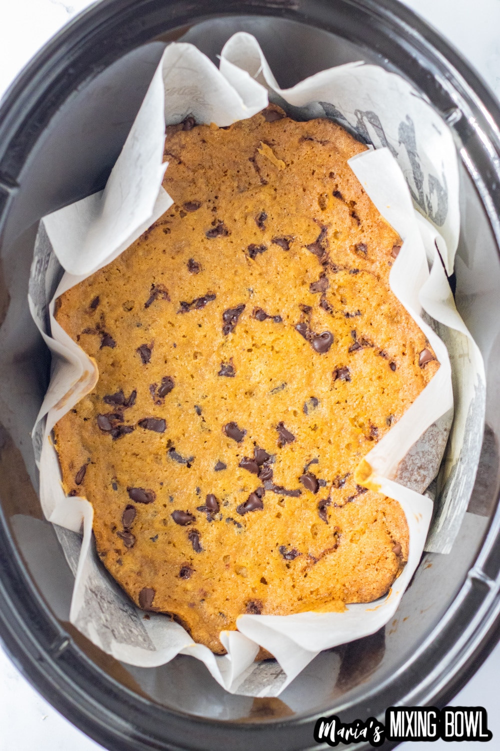 baked cookie cake in parchment paper in the slow cooker