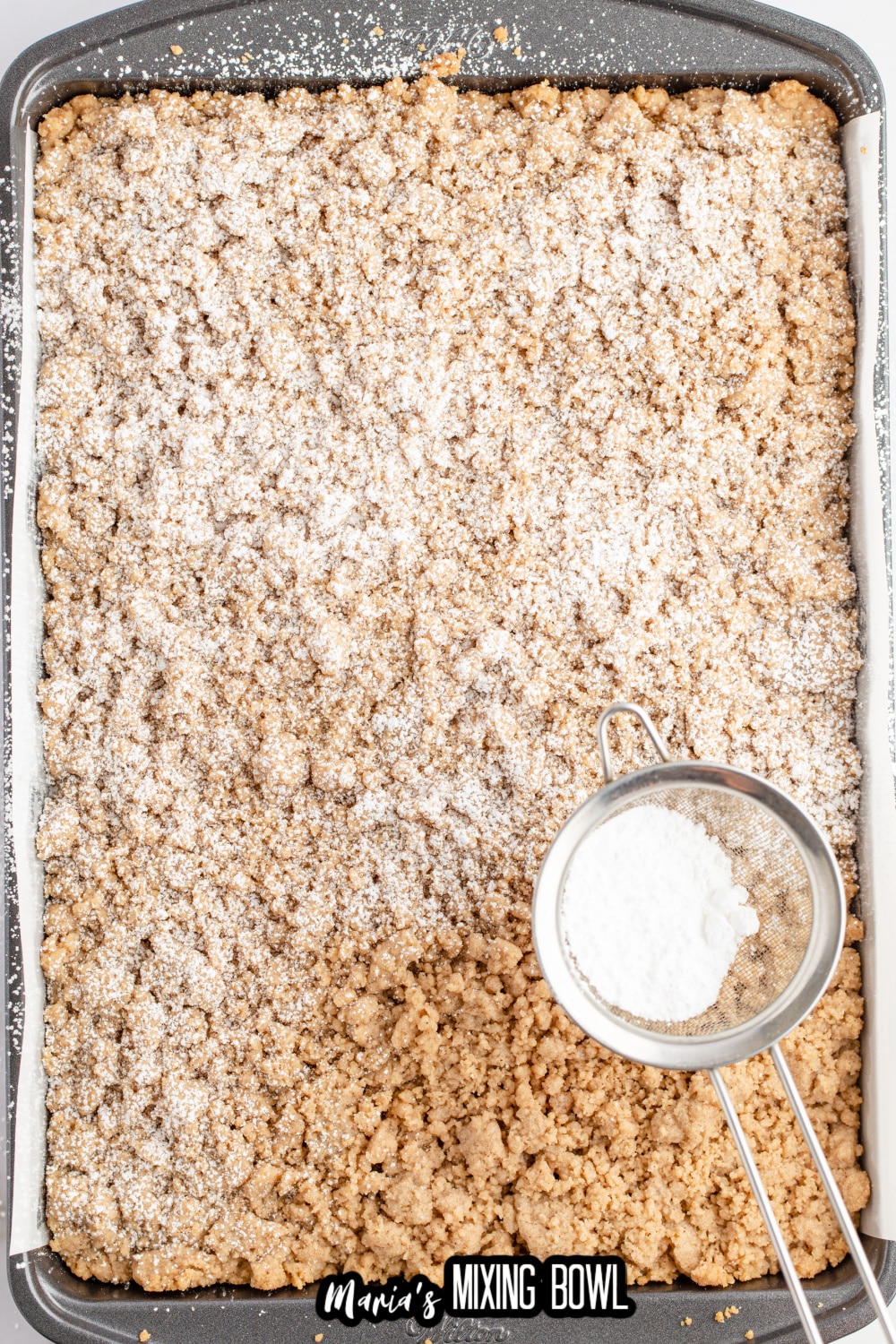 powdered sugar being sprinkled on top of a baked cake in the pan