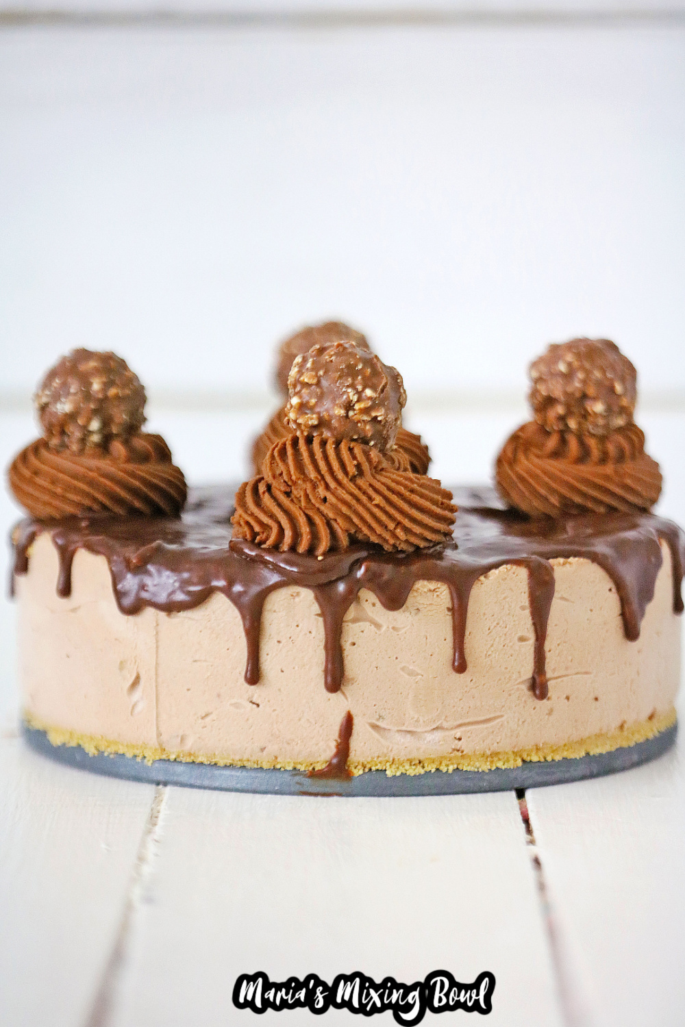 uncut ferrero roche cheesecake on a white wooden background