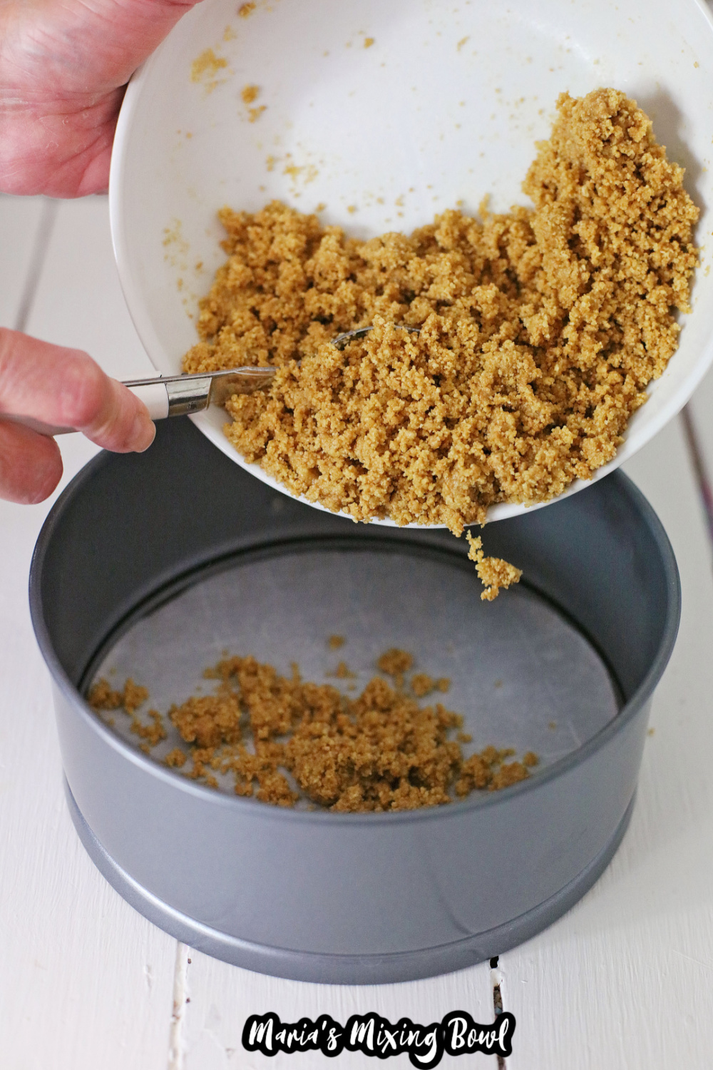 graham cracker crumbs being poured into a springform pan