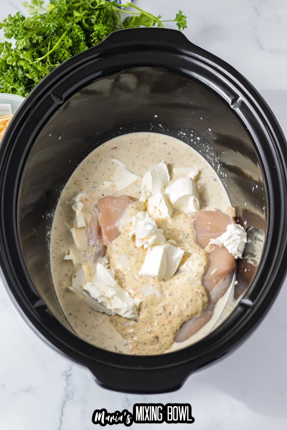 raw chicken, cream cheese, and sauce in a slow cooker