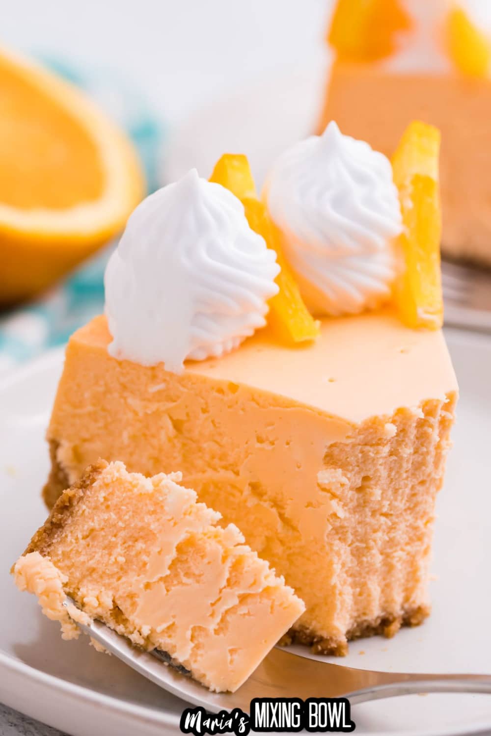 slice of cheesecake on a white plate with a bite on a fork