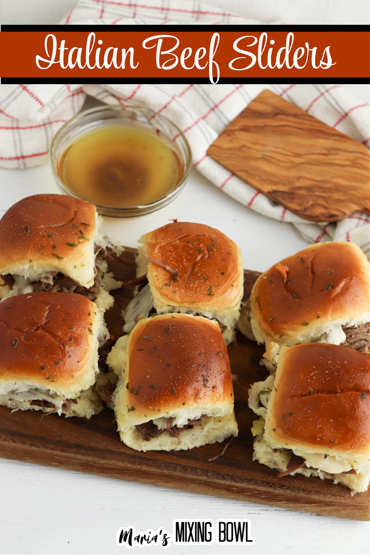 six italian beef sliders on a wooden cutting board with a bowl of au jus in the background
