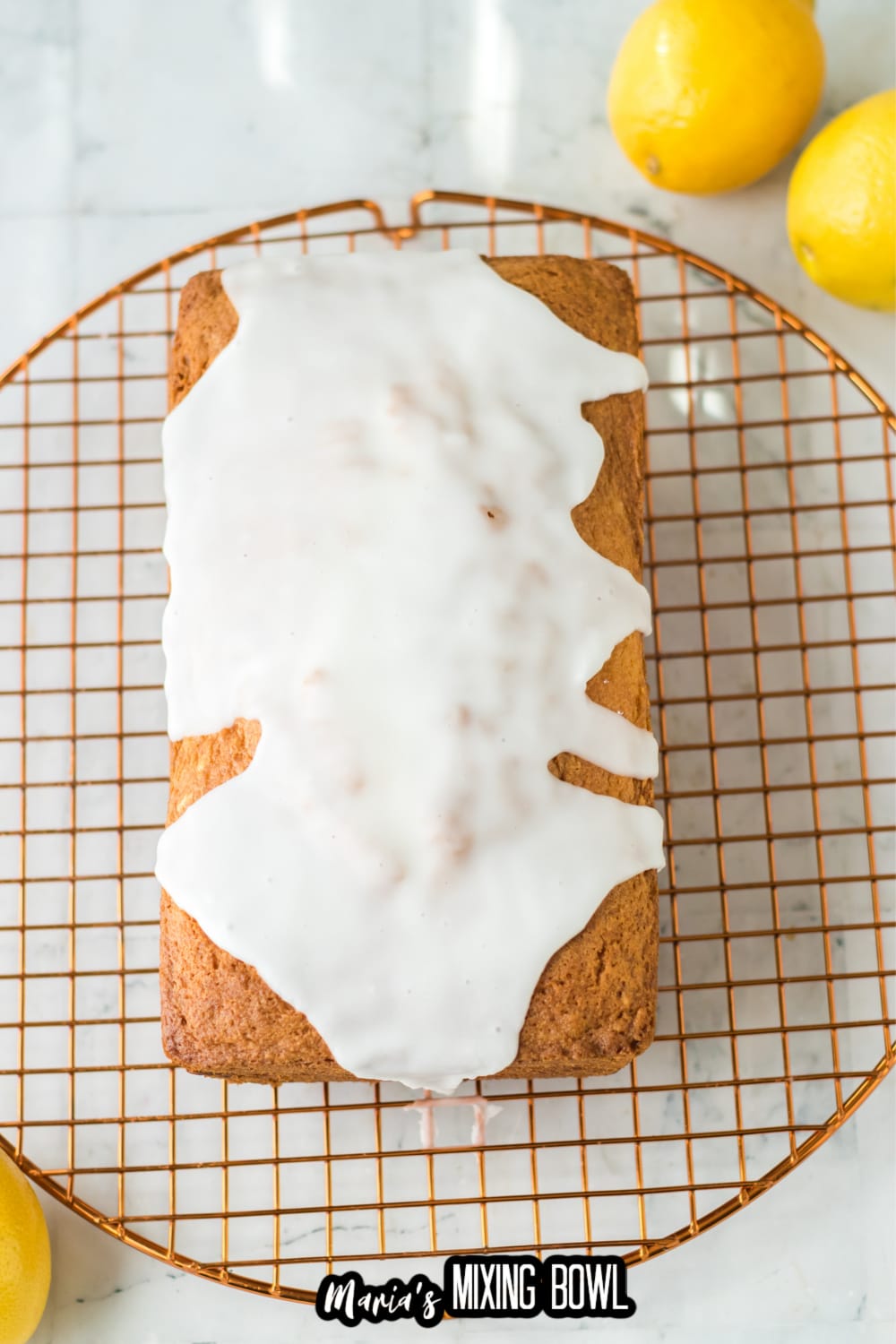 lemon loaf being glazed on a wire cooling rack
