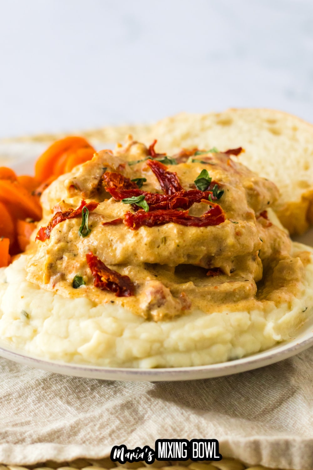 marry me pork chops stacked on top of mashed potatoes on a white plate