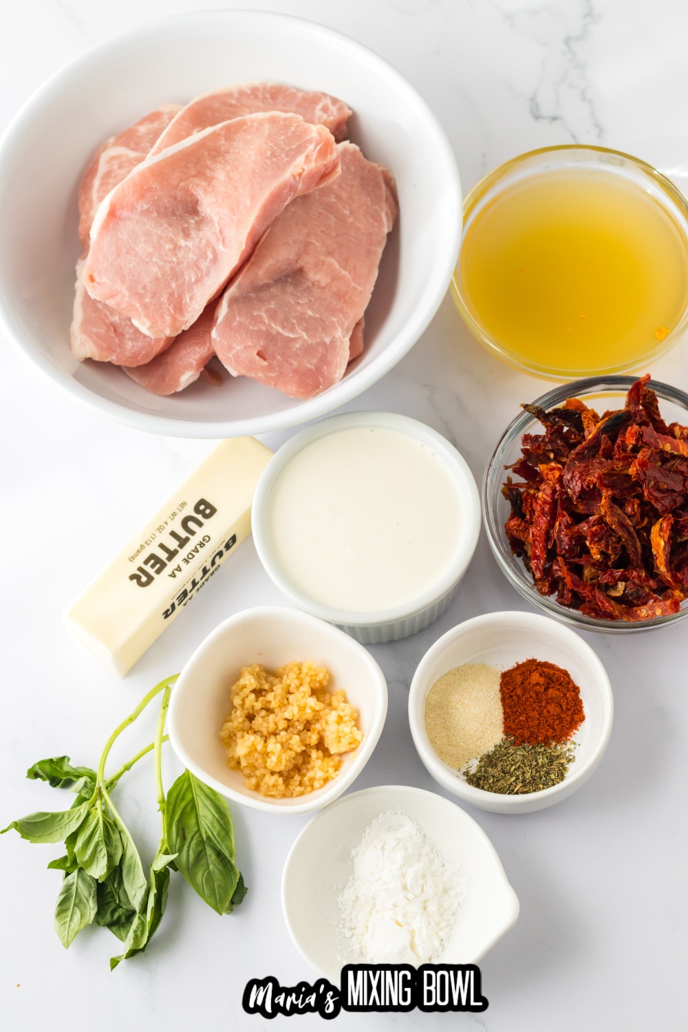 pork chops, broth, sundried tomatoes, sundried tomatoes, seasonings and garlic on a white background