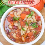 white bowl on a wooden hot pad filled with minestrone soup