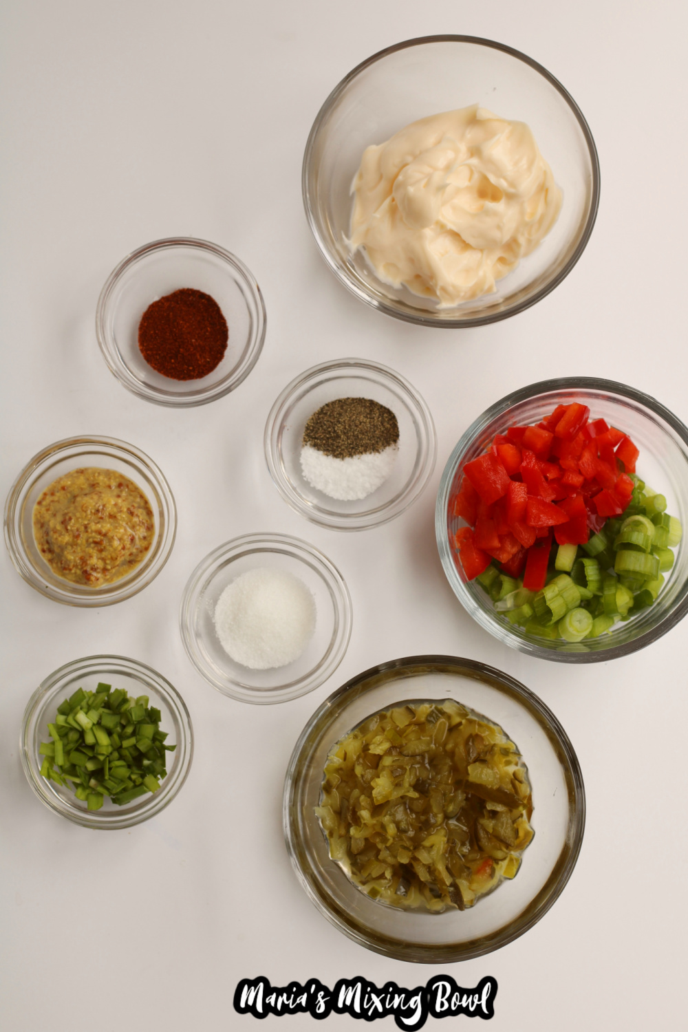 mayo, seasonings, bell pepper, and relish in small bowls on a white background