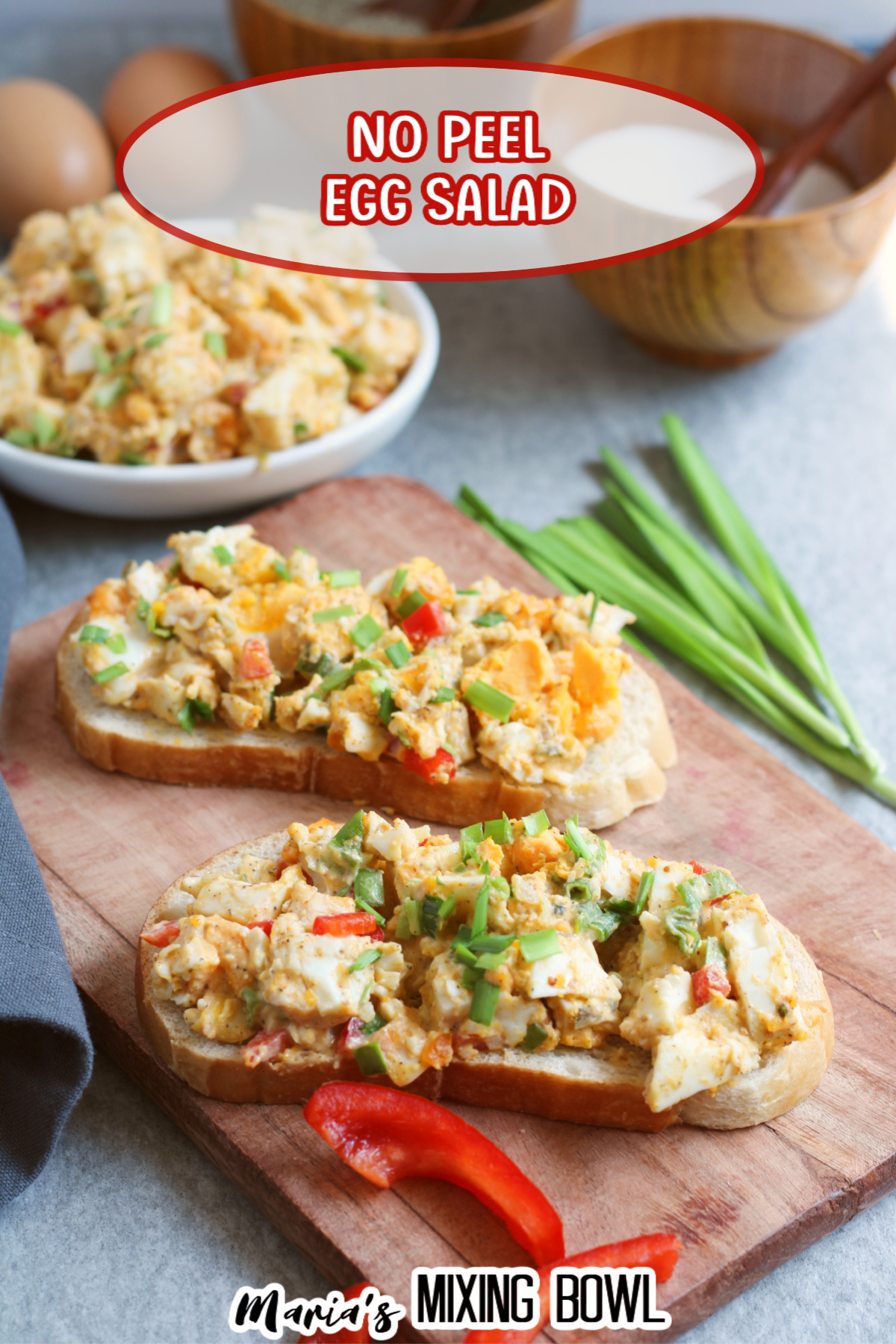 egg salad on two pieces of bread on a wooden cutting board