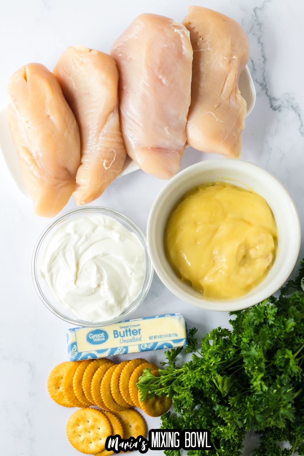 chicken breasts, cream of chicken soup, sour cream, butter, ritz crackers and parsley on a marble counter