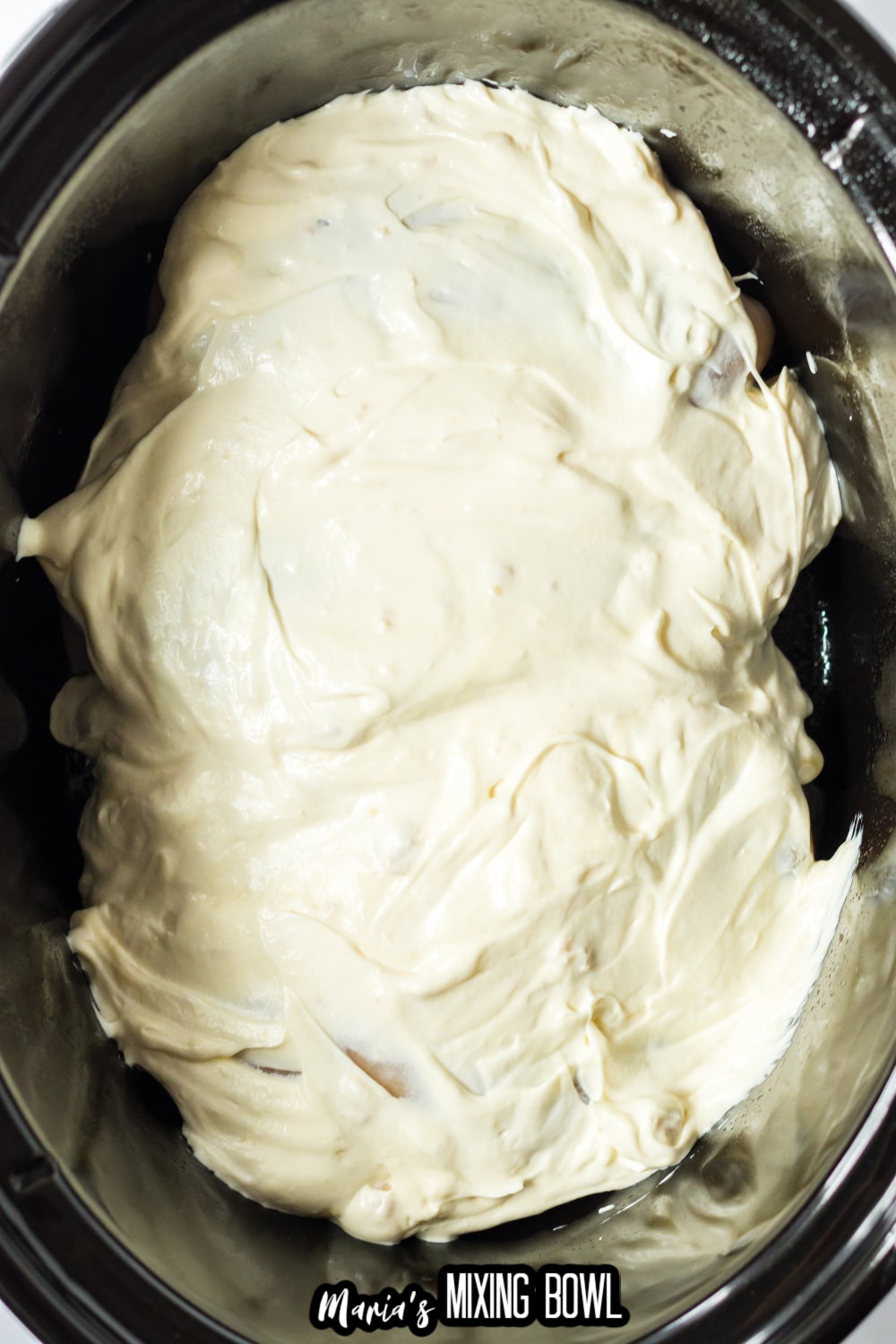 sour cream and chicken soup cream on top of raw chicken breasts in the slow cooker