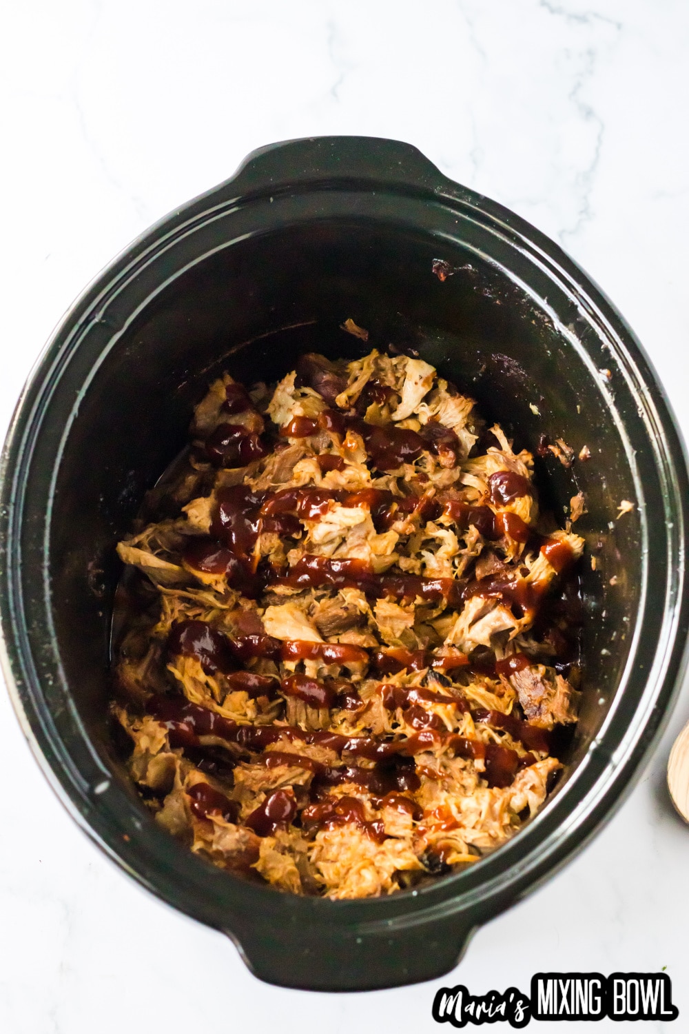 shredded pork in a slow cooker liner topped with bbq sauce