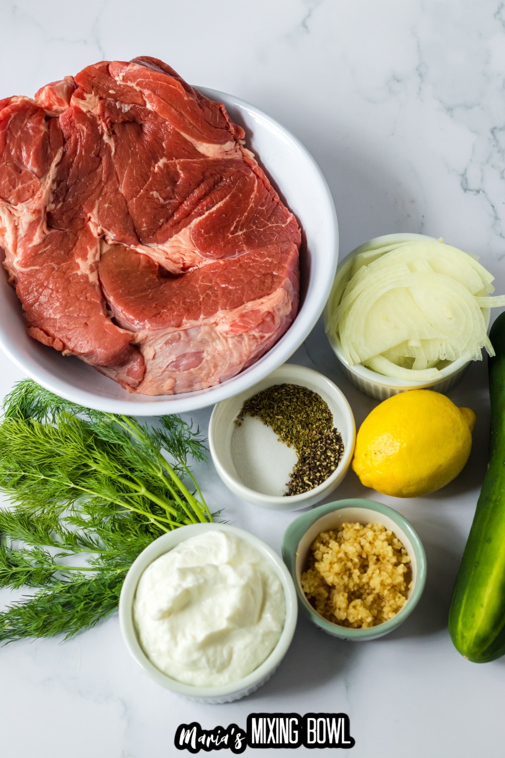 chuck roast, onions, seasonings, yogurt, lemon and garlic on a white marble background