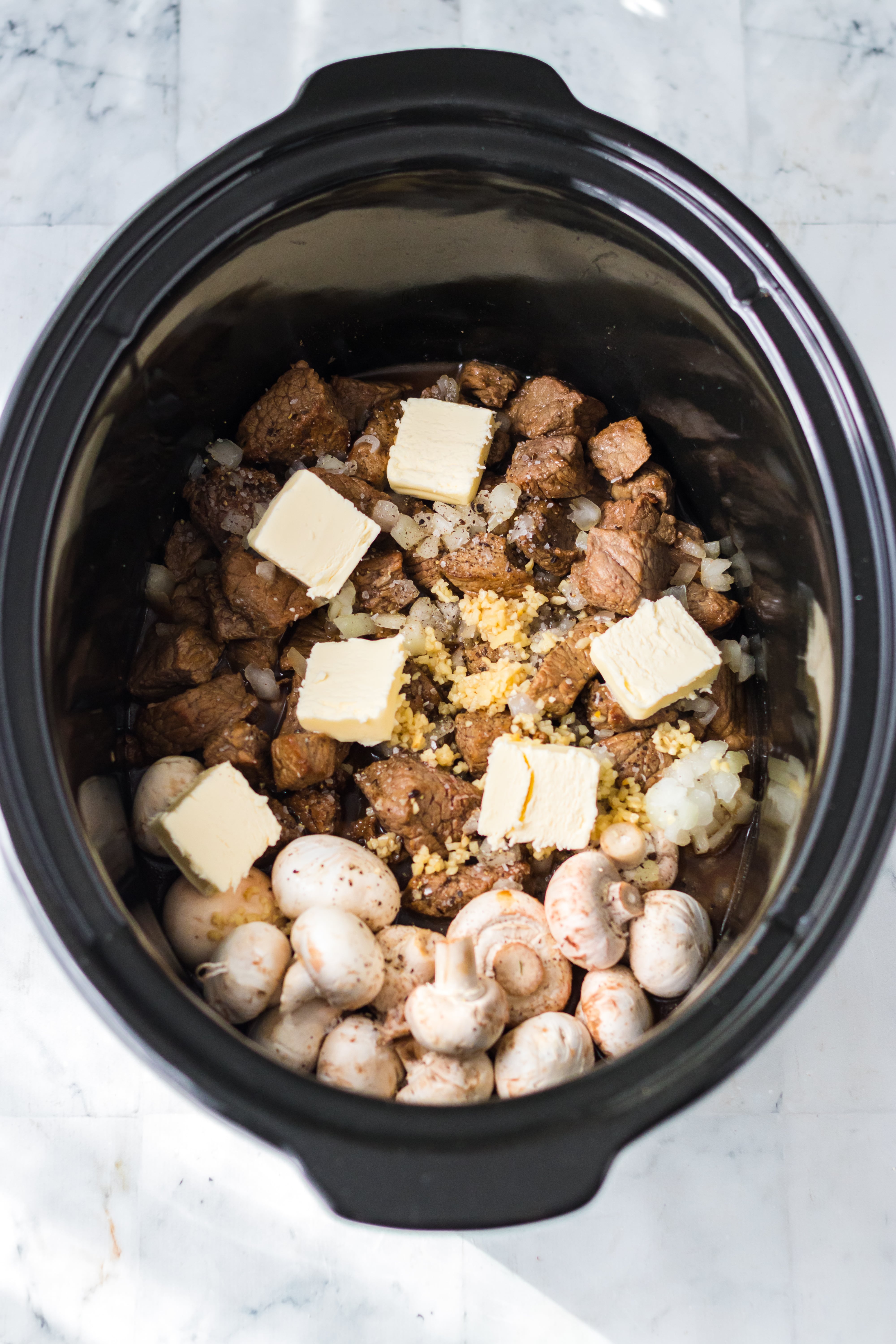 mushrooms, butter, and beef in a slow cooker 
