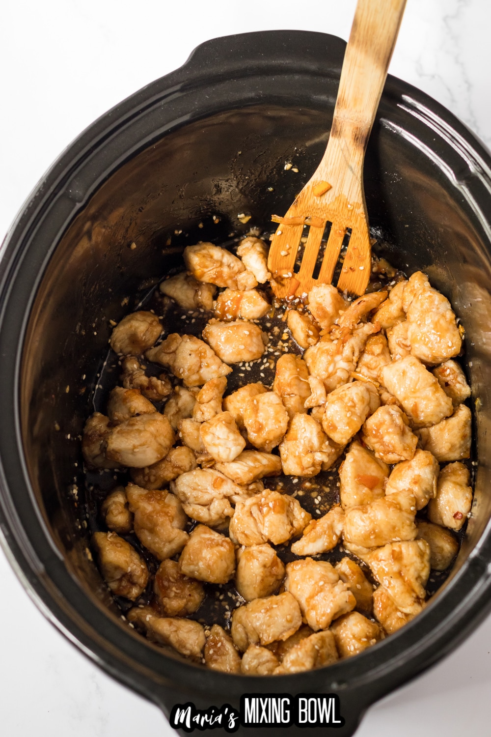 chicken being topped with sauce in a slow cooker