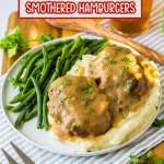 two smothered hamburgers on top of a bed of mashed potatoes with a side of green beans.