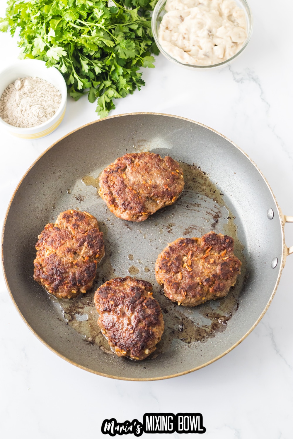 hamburger patties being browned in a large skillet