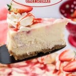slice of strawberry swirl cheesecake on a cake cutter held in the air