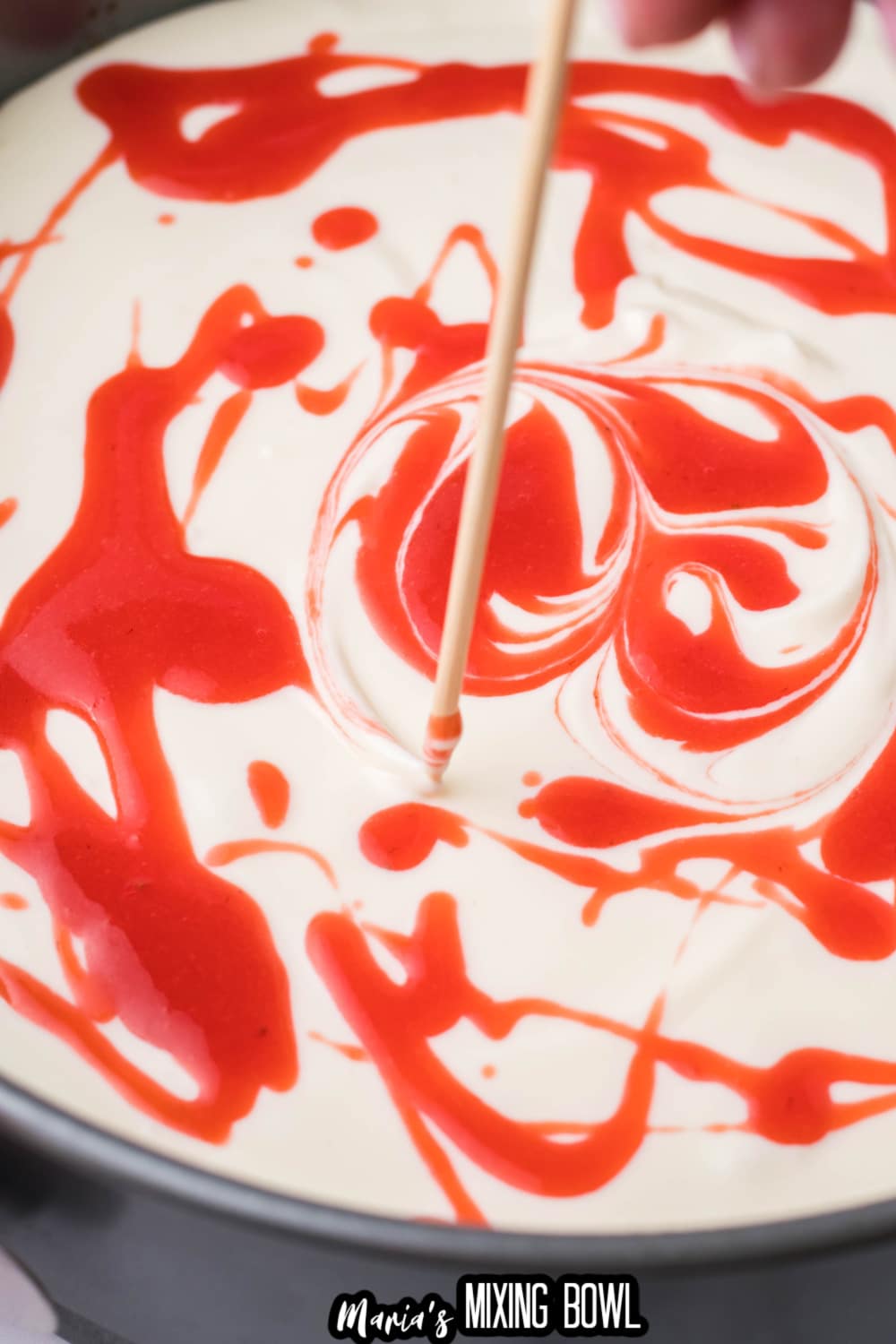 strawberry being swirled into a springform pan