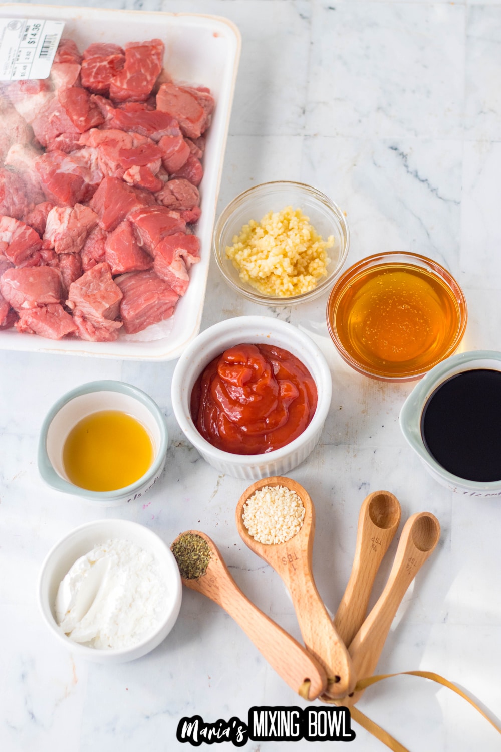 steak tips, ketchup, garlic, honey, soy sauce, and seasonings on a marble backdrop