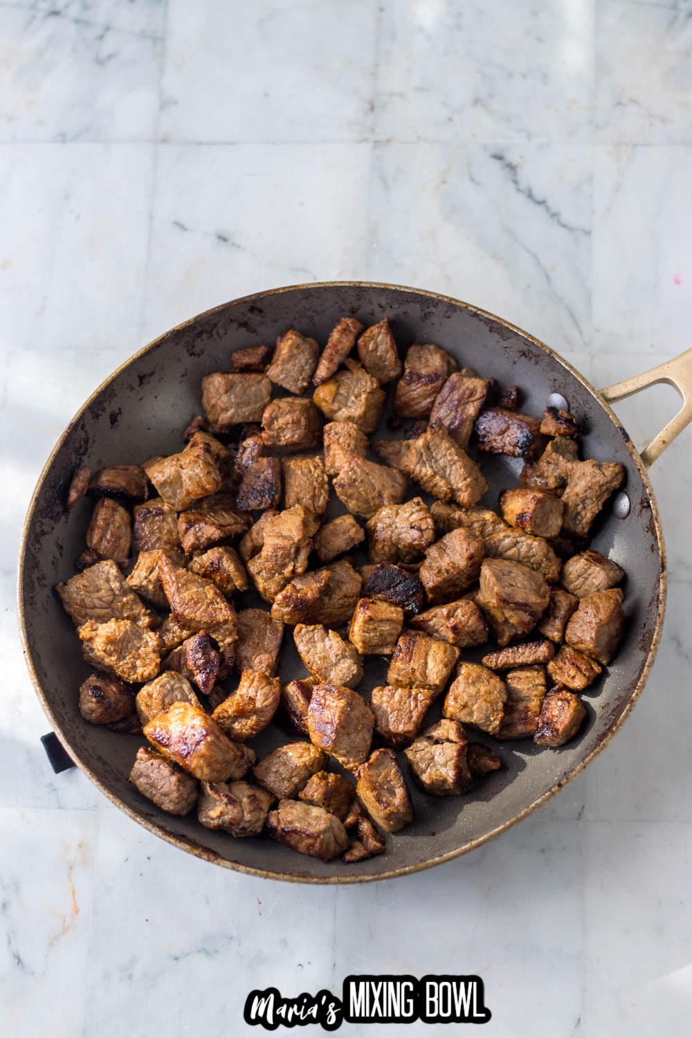 steak tips in being browned in a skillet