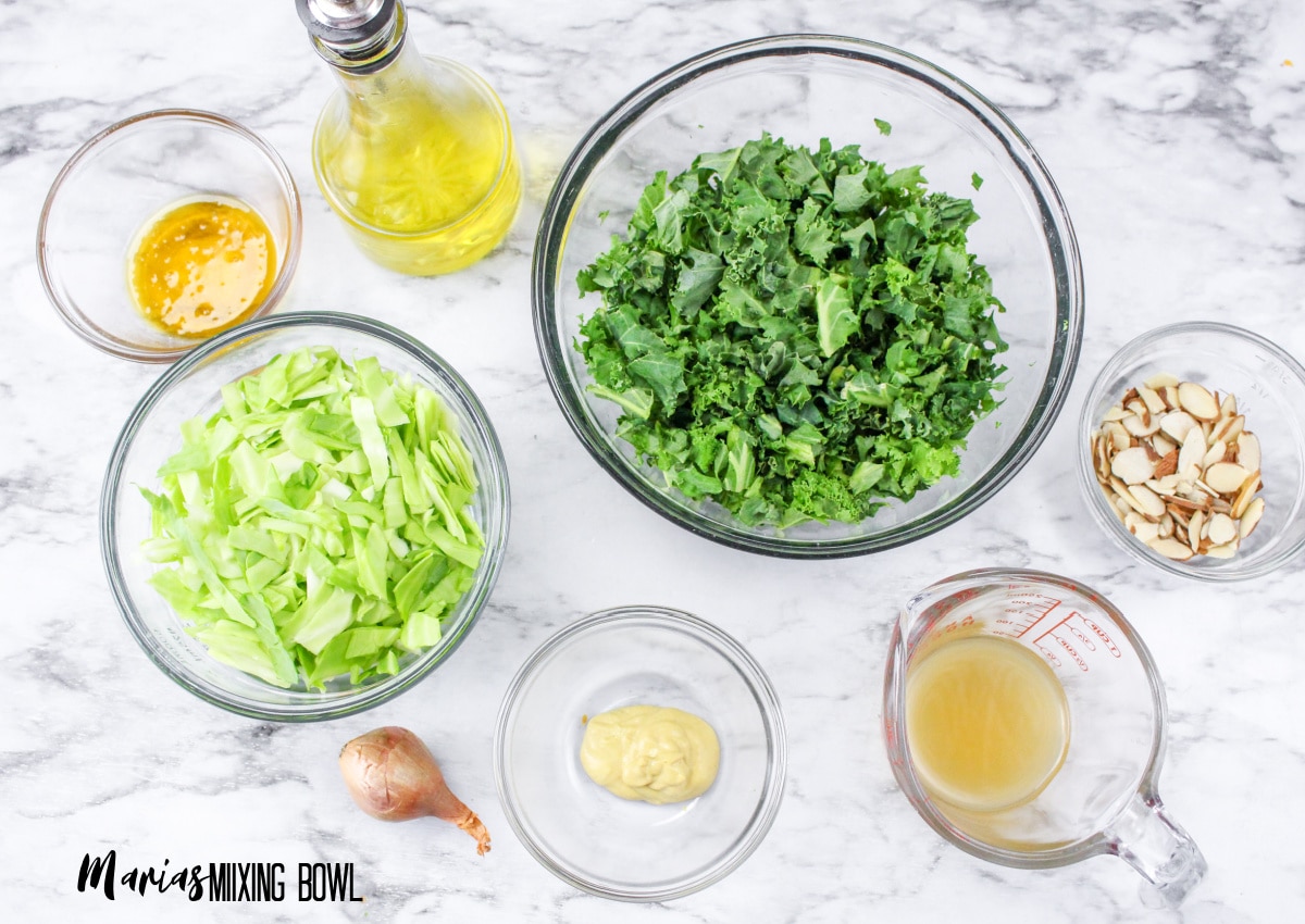 bowls of kale, cabbage, sliced almonds, vinegar, oil, and mustard.