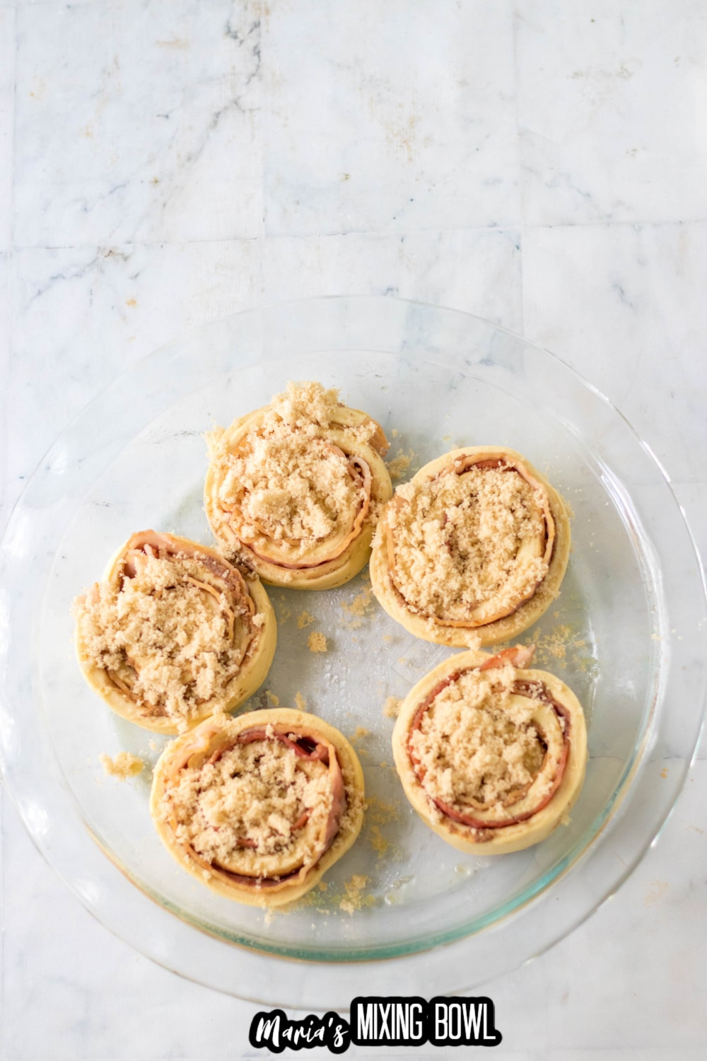 uncooked cinnamon rolls on a glass pie plate