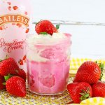 mason jar filled with strawberry mug cake and topped with whipped cream and a fresh strawberry