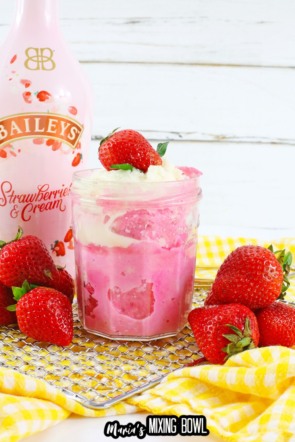 mason jar filled with strawberry mug cake and topped with whipped cream and a fresh strawberry