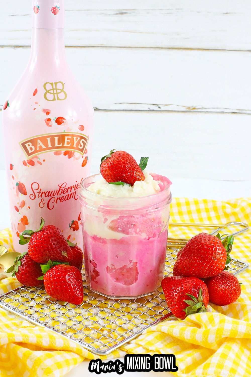 mason jar filled with strawberry mug cake and topped with whipped cream and a fresh strawberry