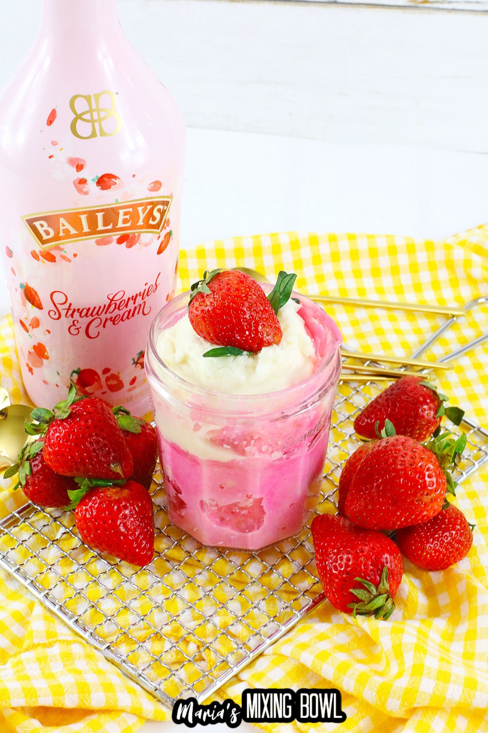 mason jar filled with strawberry mug cake and topped with whipped cream and a fresh strawberry