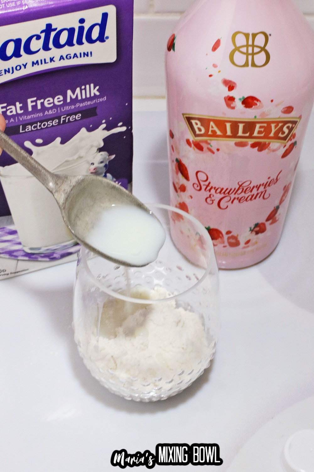 milk being added to a glass with a bottle of baileys in the background