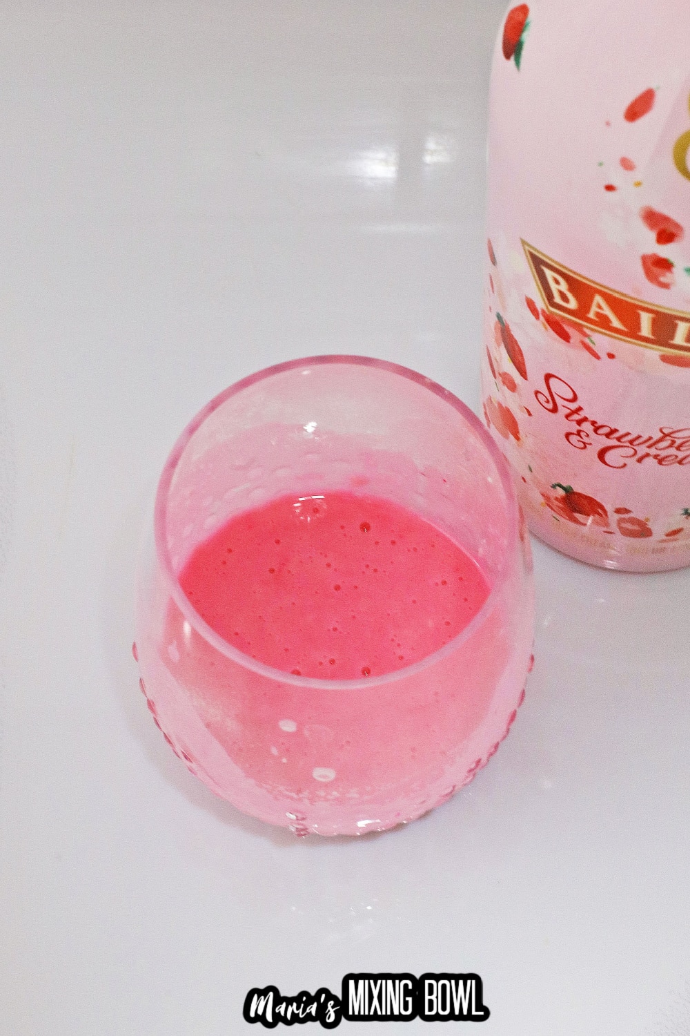 raw mug cake batter in a glass with a bottle of strawberry baileys in the background