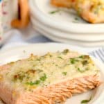 birds eye image of a baked salmon filet on a white plate that is garnished with fresh parsley
