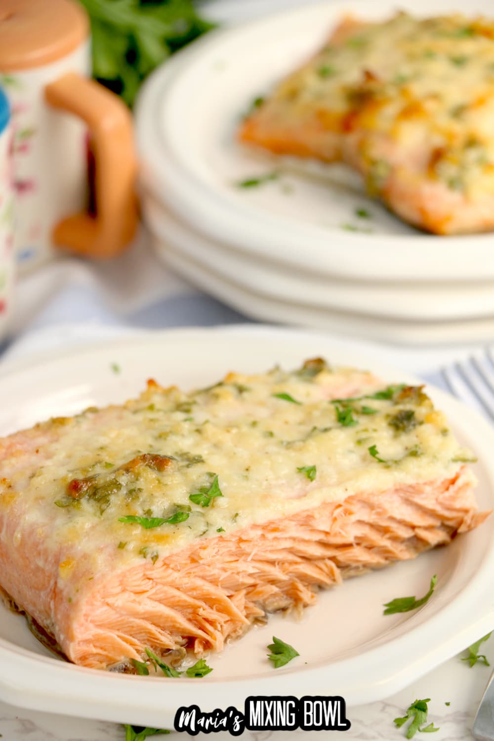 birds eye image of a baked salmon filet on a white plate that is garnished with fresh parsley