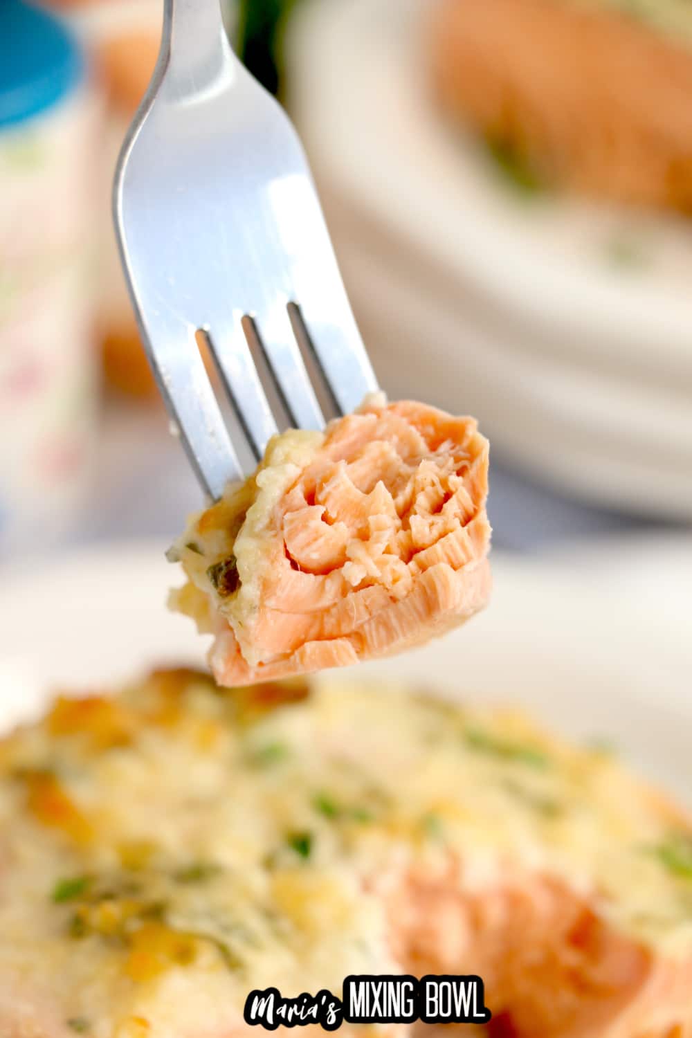 bit of baked salmon held on a fork in the air
