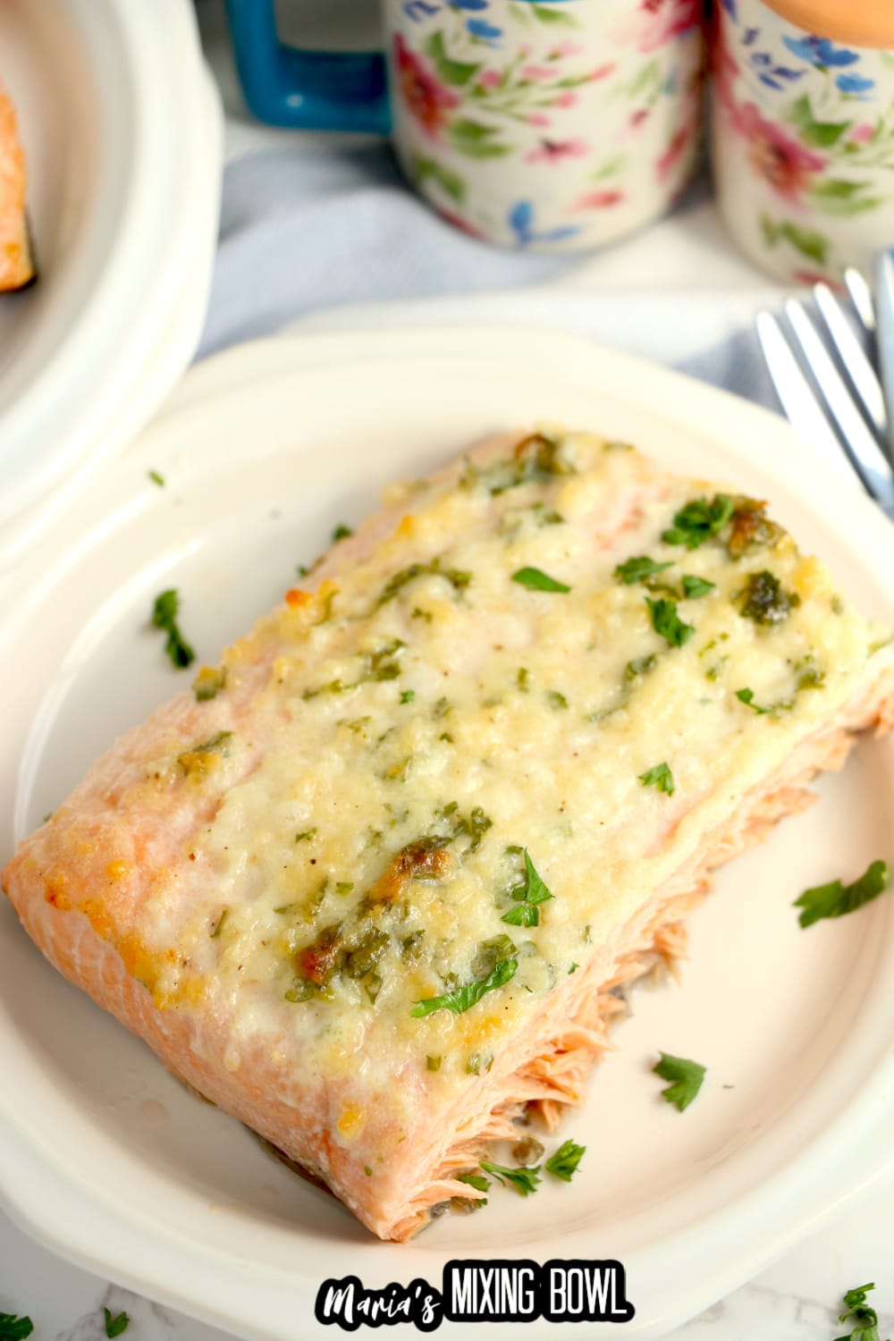 birds eye image of a baked salmon filet on a white plate that is garnished with fresh parsley