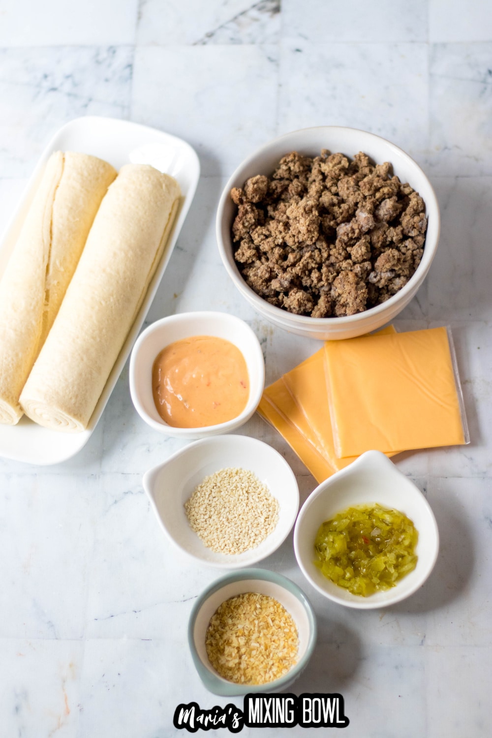 crescent roll dough, ground beef, dressing, pickles, onions, and american cheese on a white marble background