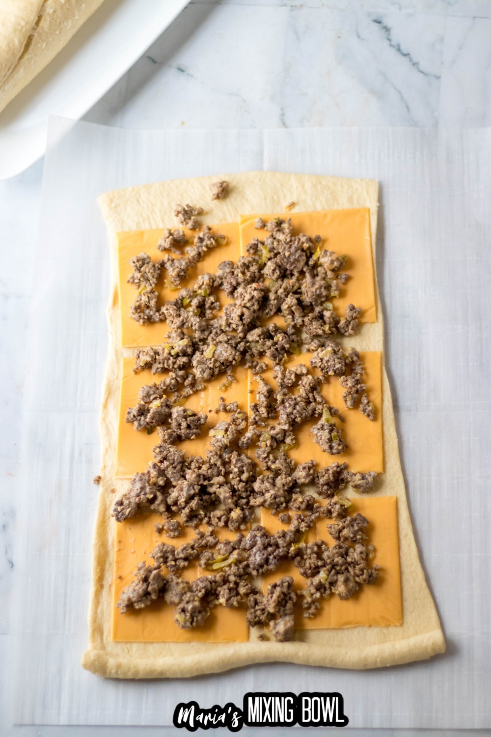 crescent roll dough rolled out and topped with american cheese and ground beef