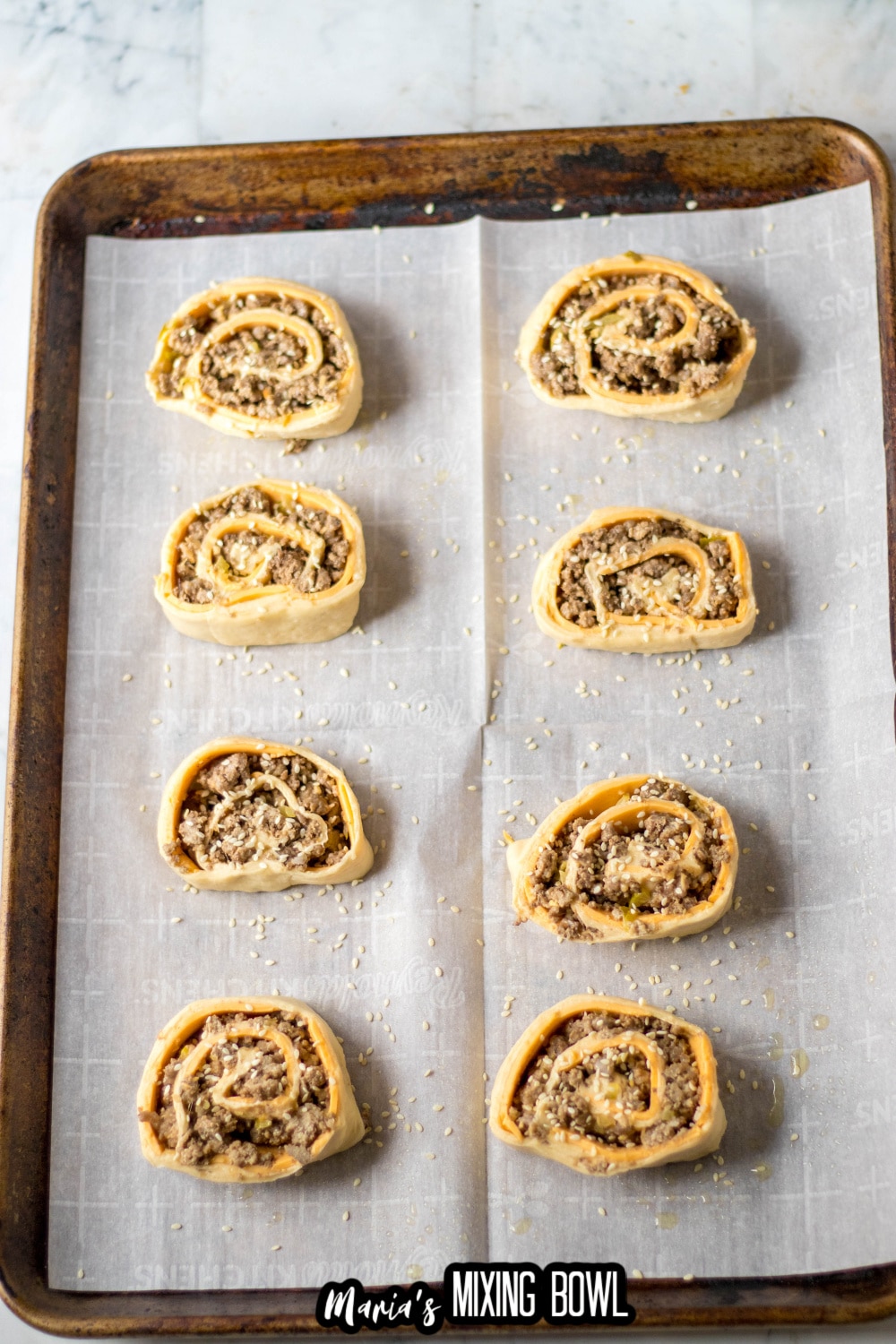 uncooked big mac pinwheels on a parchment lined baking sheet