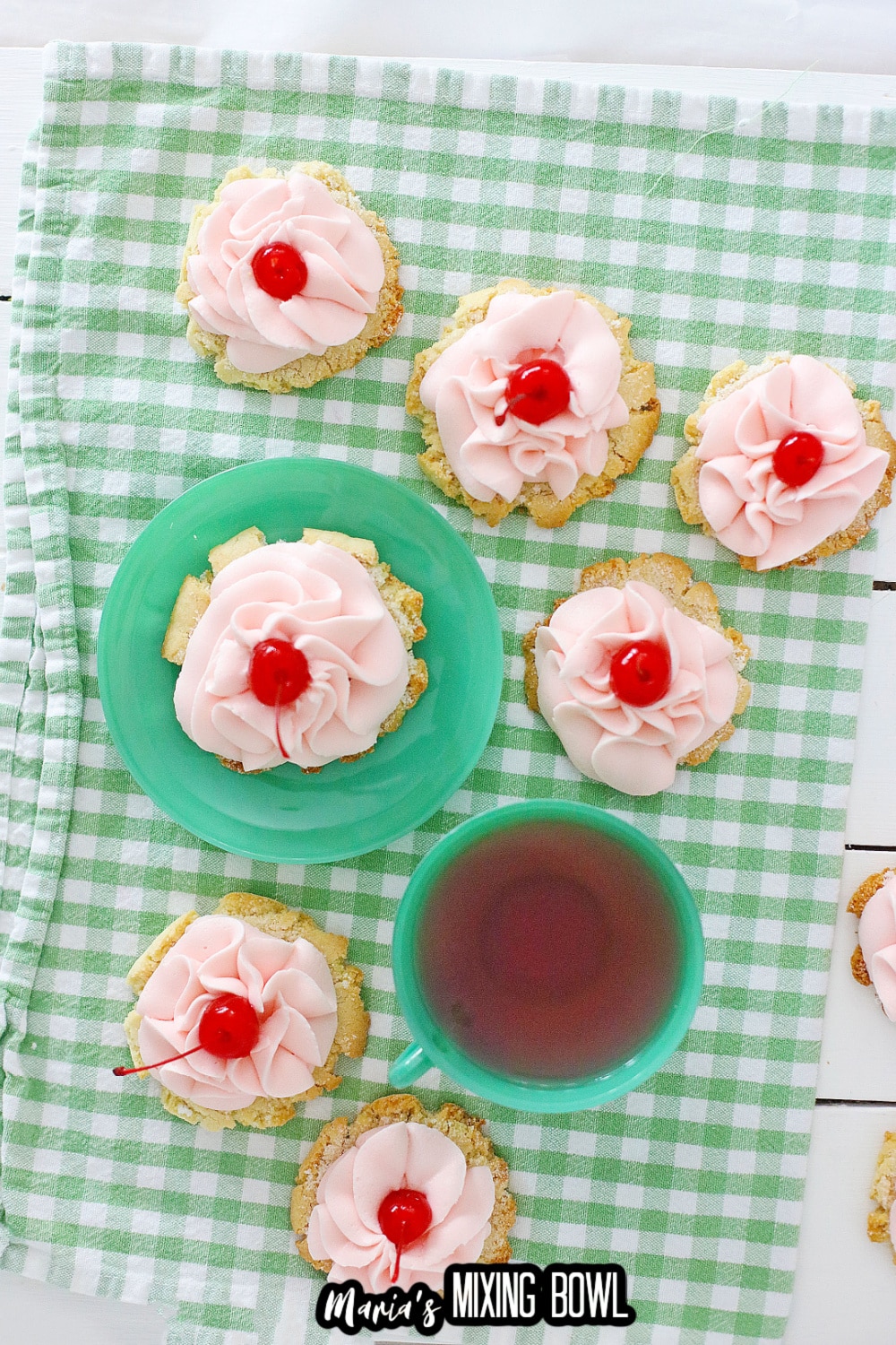 six cherry cookies on a green and white kitchen towels