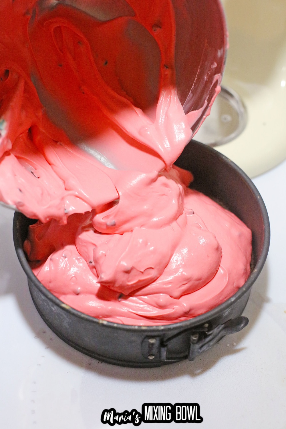 cherry cheesecake batter being poured into a springform pan