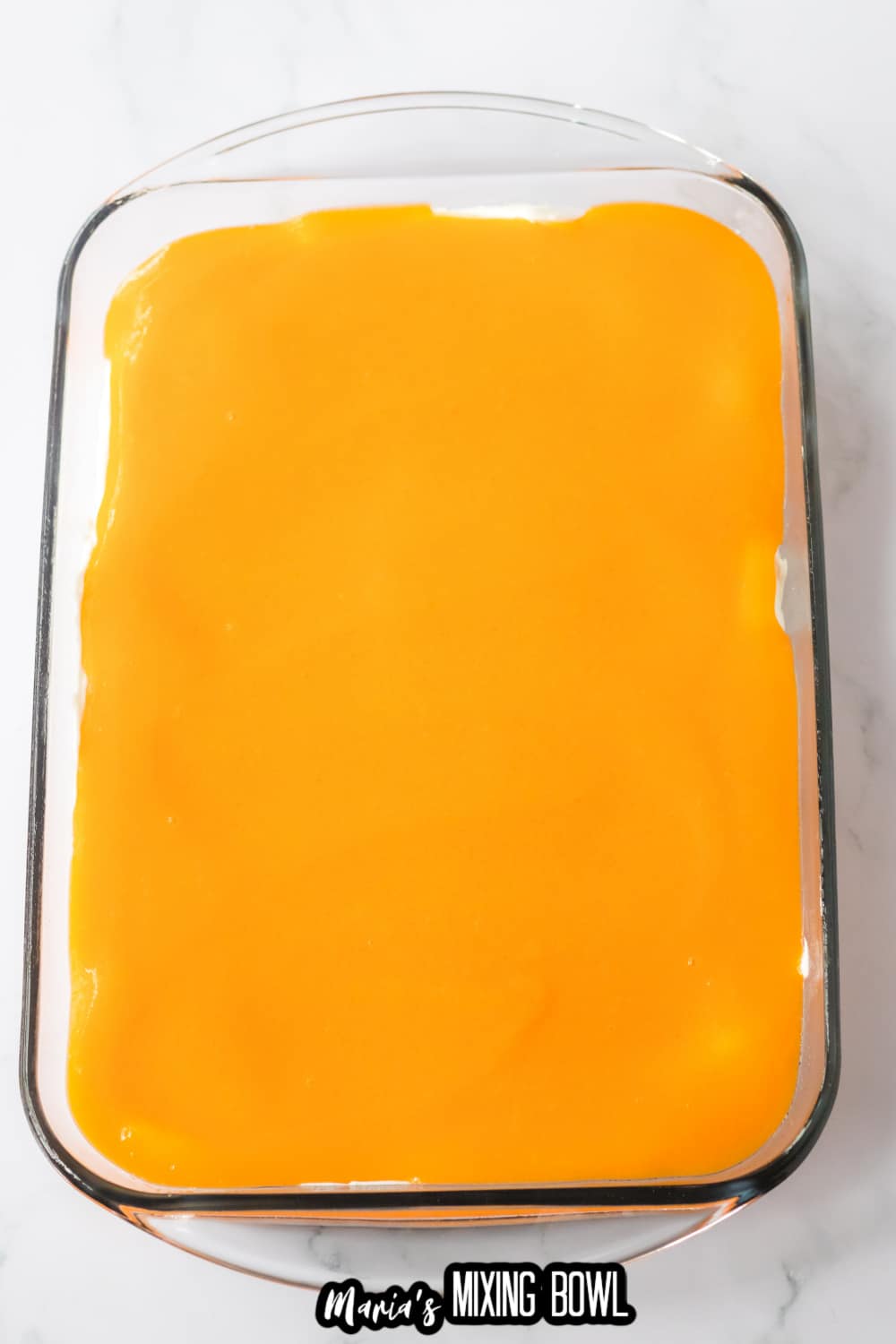 orange layer being added to a glass baking dish